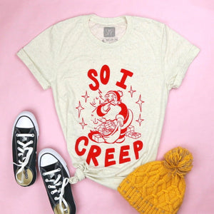 An image of the So I Creep Santa novelty Christmas shirt with props from Saturday Morning pancakes.